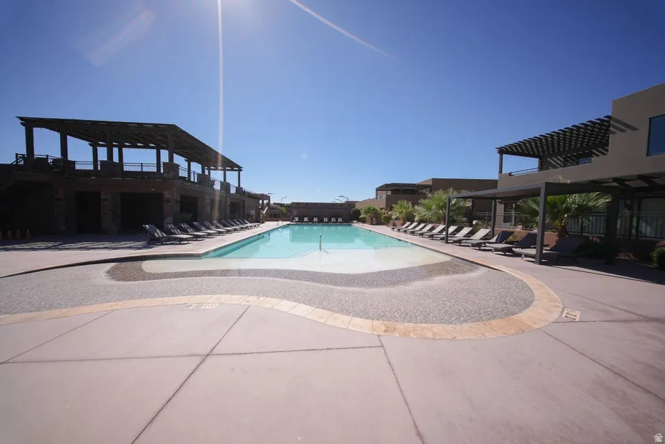 Expansive outdoor swimming pool with integrated tanning ledge, surrounded by a concrete deck with decorative stone accents
