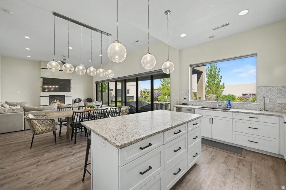 Spacious kitchen with a large island, white cabinetry, herringbone tile backsplash, and wood-finish flooring