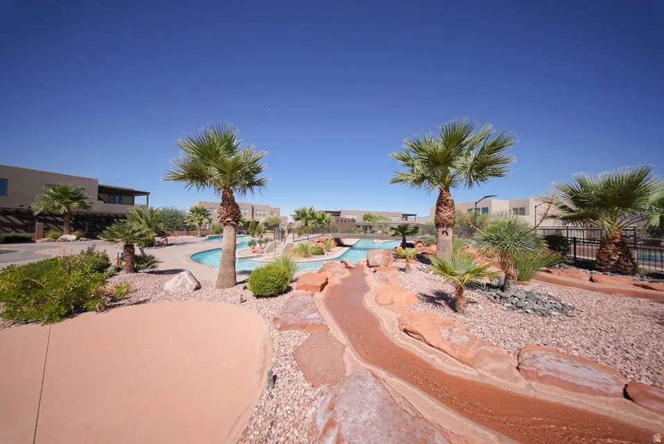 Expansive outdoor recreation area with a winding pool, mature palm trees, and decorative rock landscaping