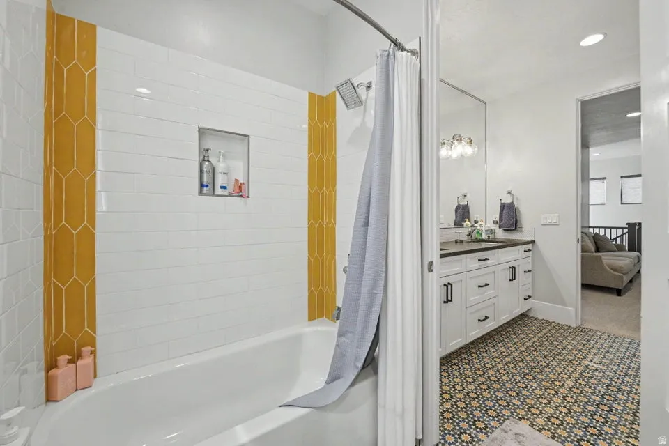 Bathtub and shower combination with white subway tile and decorative yellow accent tiles