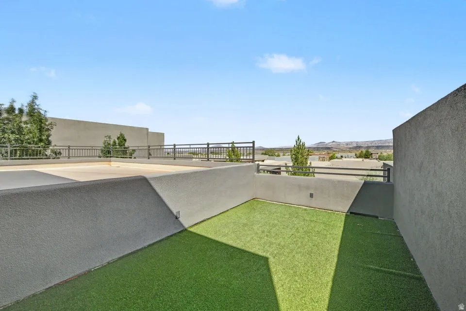 Modern backyard retreat featuring a sunken lounge area with concrete retaining walls, dual-tone synthetic turf in contrasting green hues, and mature landscaping