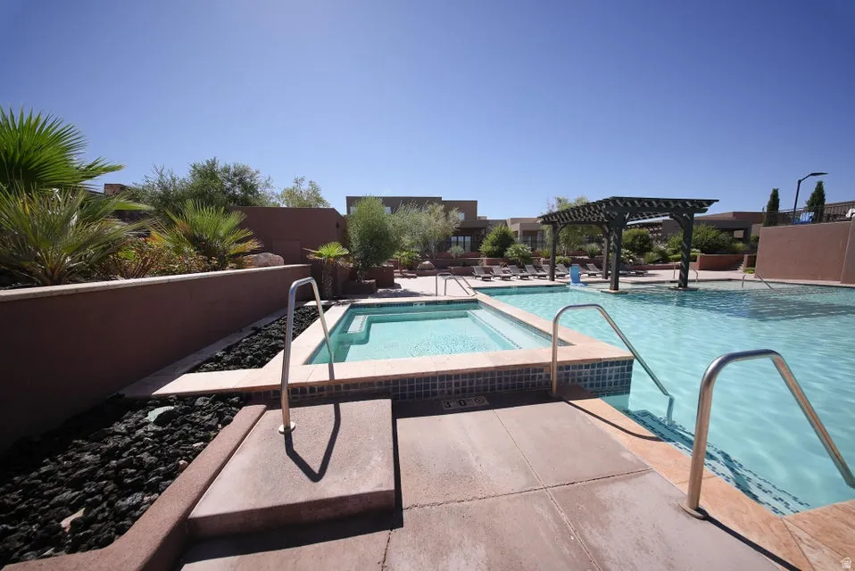 Resort-style pool area featuring multiple swimming pools with metal handrails, concrete decking, and integrated spa