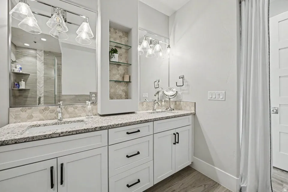 Dual vanity with granite countertops, undermount sinks, and white shaker cabinetry