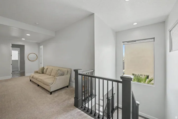 Carpeted landing with recessed lighting, a built-in window, and a dark-finish stair railing