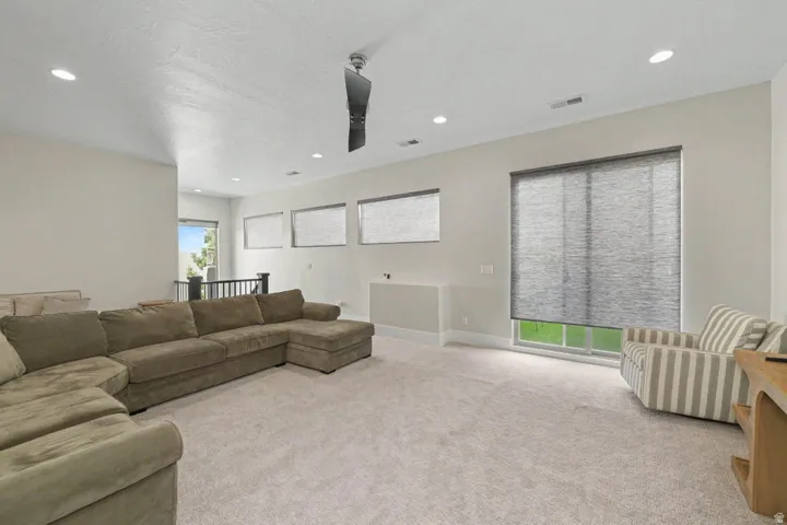 Recessed lighting, ceiling fan, and multiple windows with roller shades