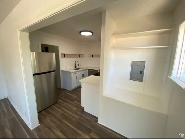 Kitchen featuring wood-finish flooring, white cabinetry, a single basin sink with a matte black faucet, and stainless steel appliances