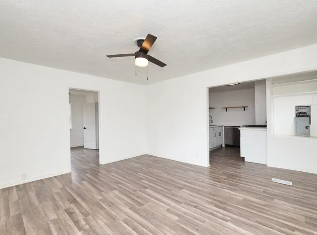 Wood-finish flooring throughout, white painted walls, and a contemporary ceiling fan