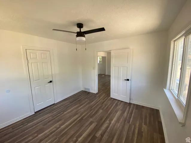 Wood-finish flooring, white paneled doors with matte black hardware, and a ceiling fan with integrated lighting