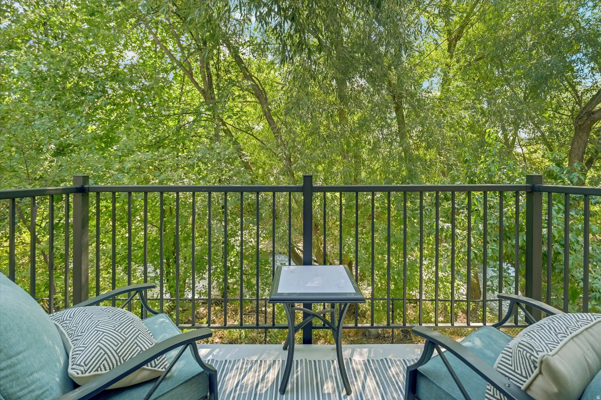Balcony with metal railing and a lush tree-filled backdrop