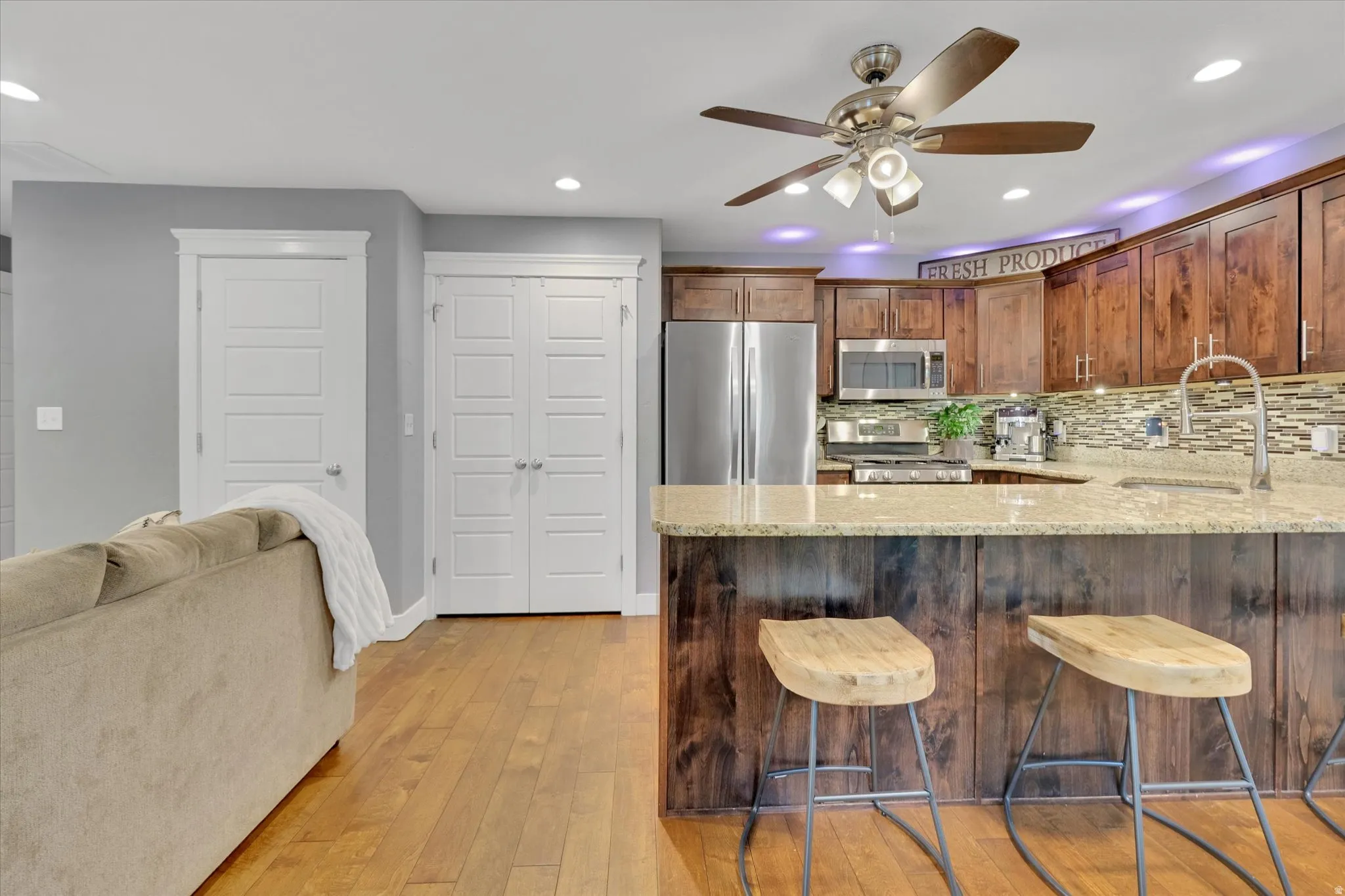 Kitchen with wood-finish flooring, stainless steel appliances, and a mosaic tile backsplash