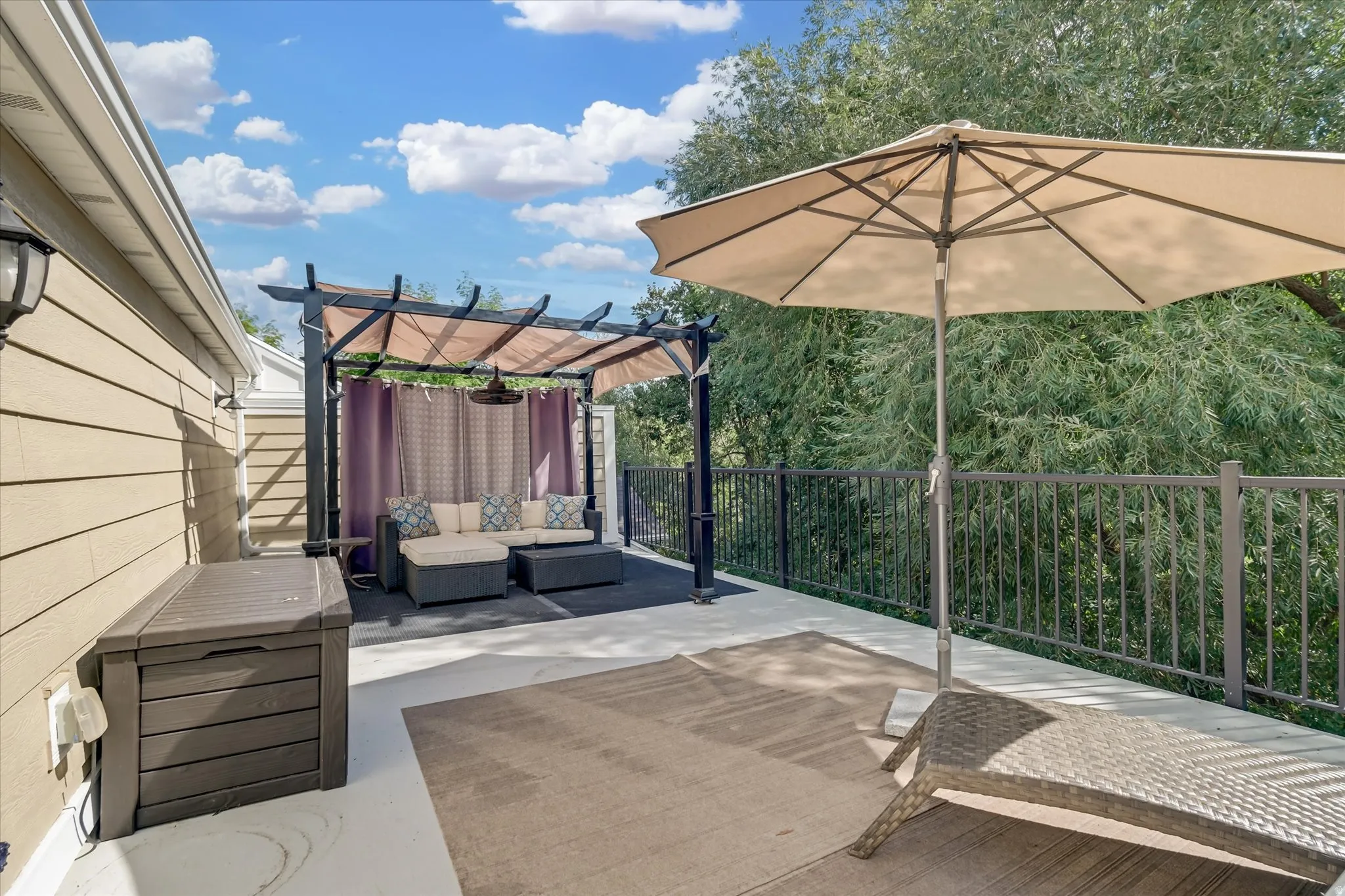 Expansive outdoor deck featuring a fixed pergola, privacy curtains, and metal railings