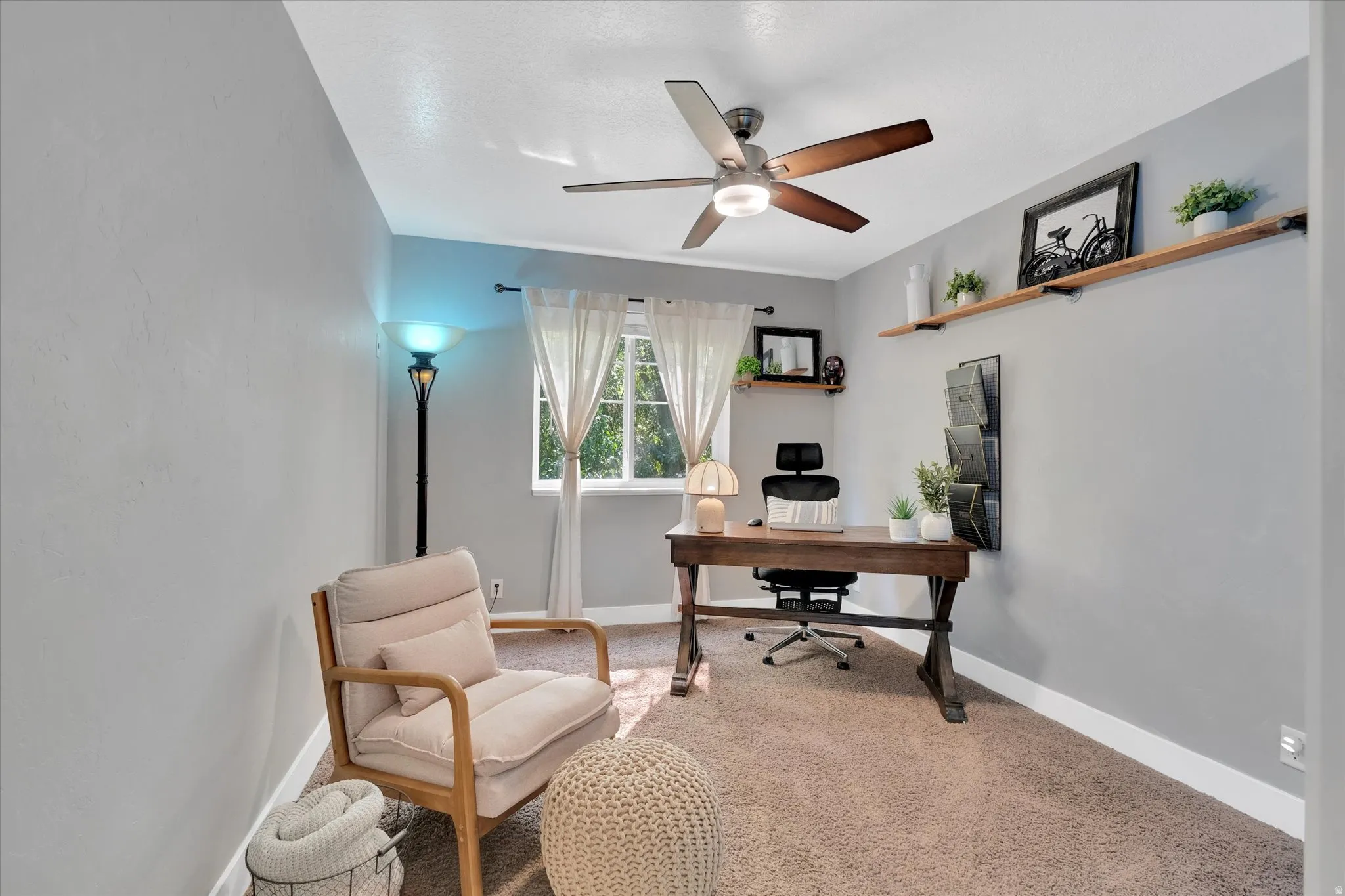Room featuring a ceiling fan with integrated lighting, wood-finish shelving, and a large window