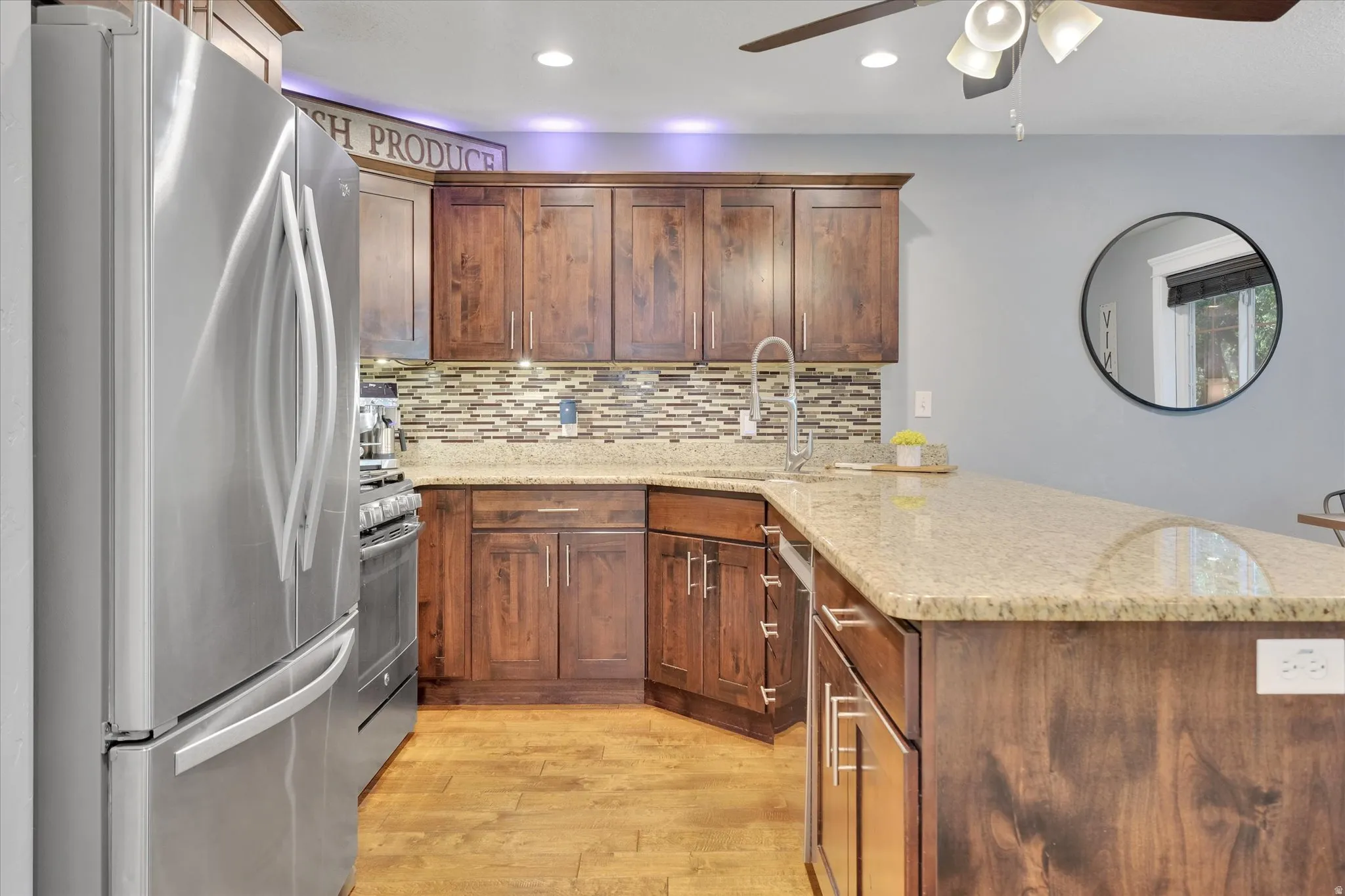 Kitchen featuring wood-finish flooring, stainless steel appliances, wood cabinetry, granite countertops, and a tile backsplash