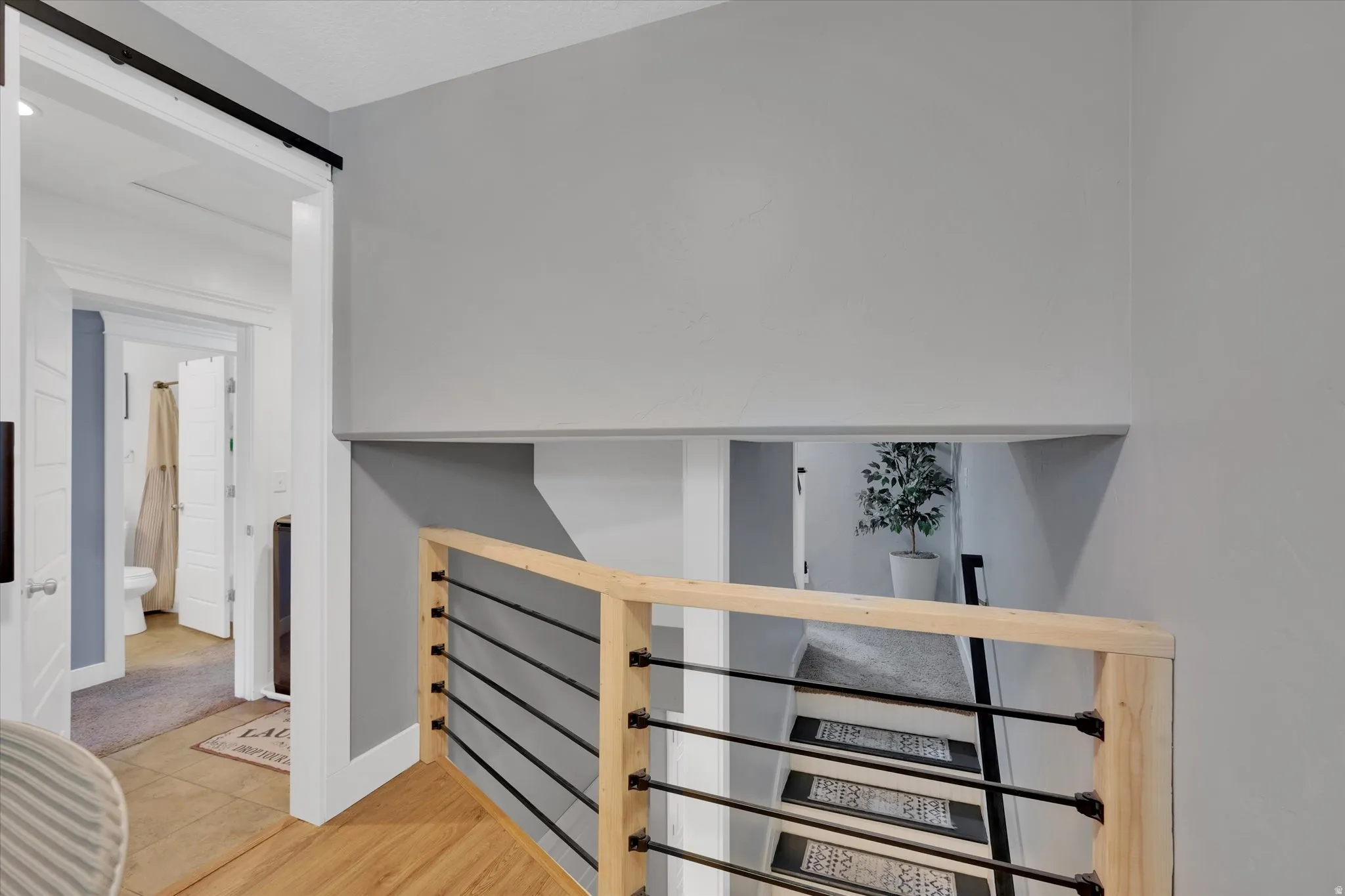 Open staircase with light wood railings and black horizontal balusters