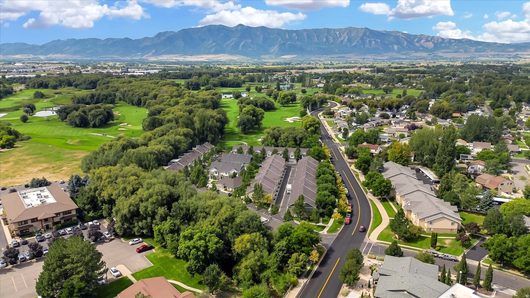 Mountain backdrop, residential area, adjacent green spaces, paved roadways, established landscaping