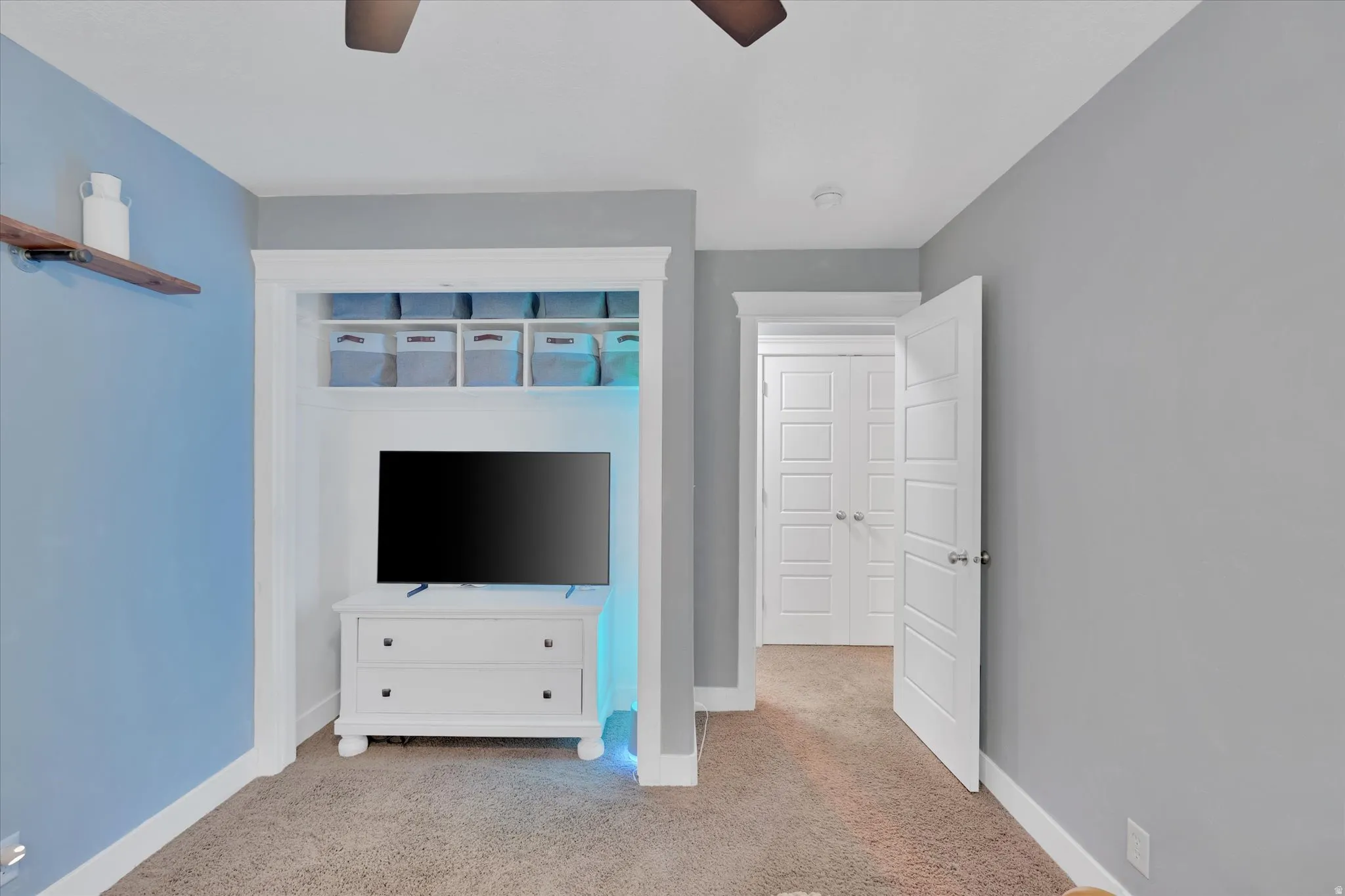 Built-in alcove shelving, wood-finish floating shelf, white paneled doors, and ceiling fan