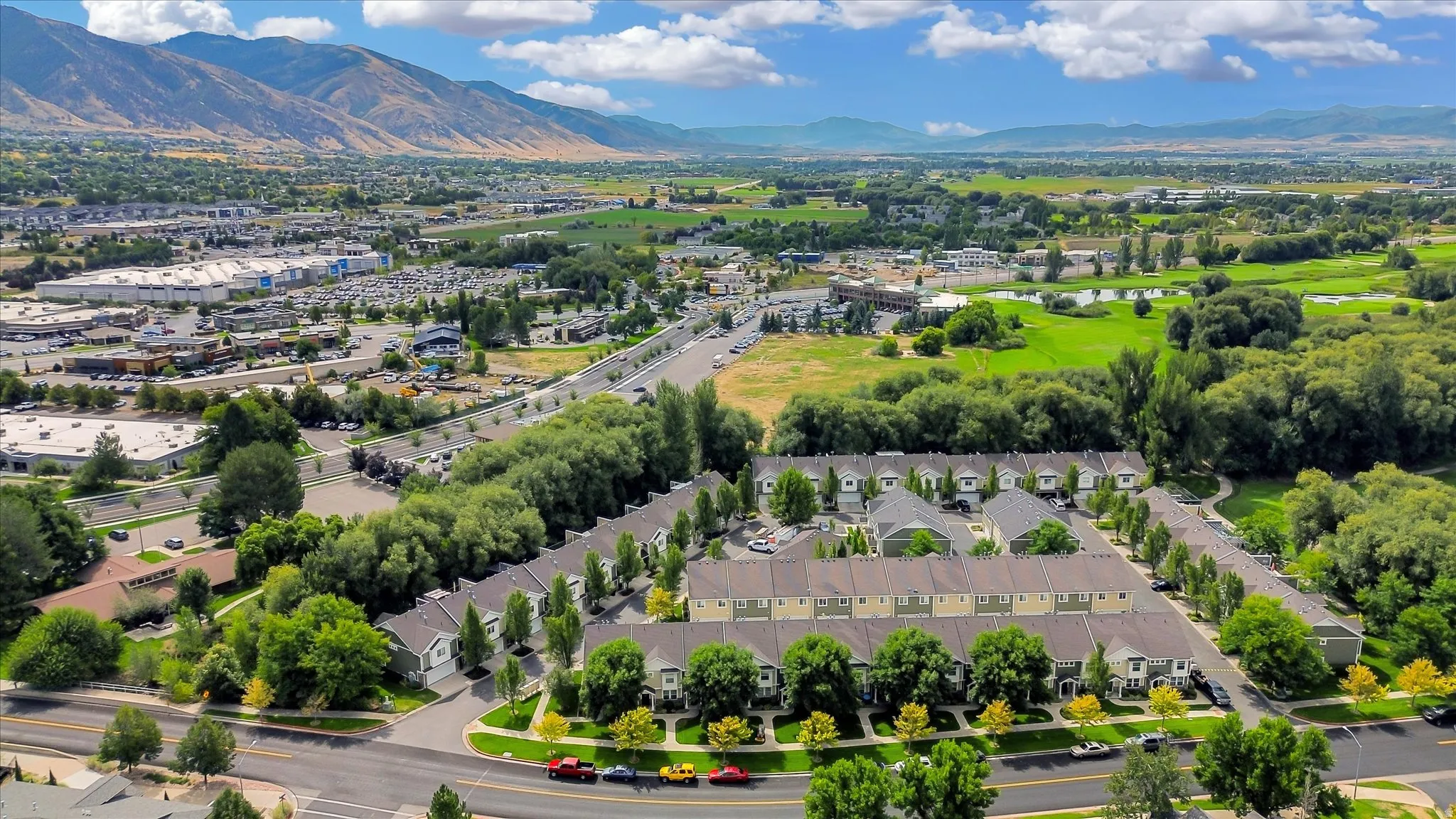 Aerial perspective featuring townhomes, surrounding green spaces, and distant mountains