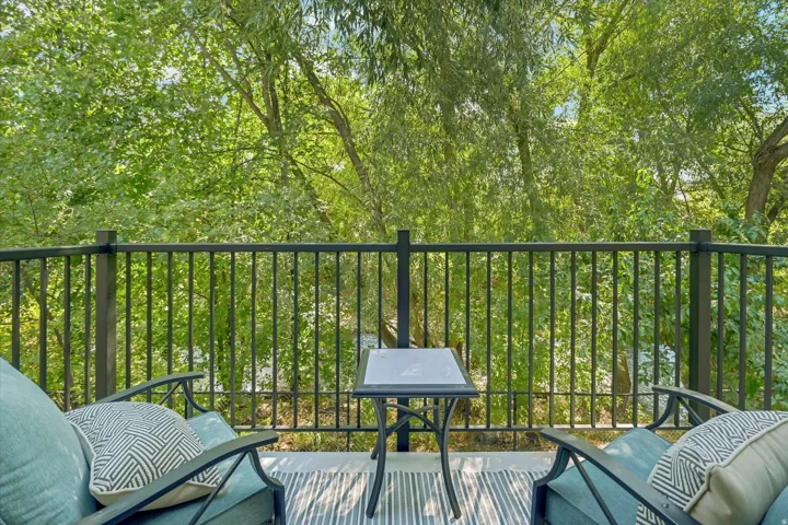 Balcony with metal railing and a lush tree-filled backdrop