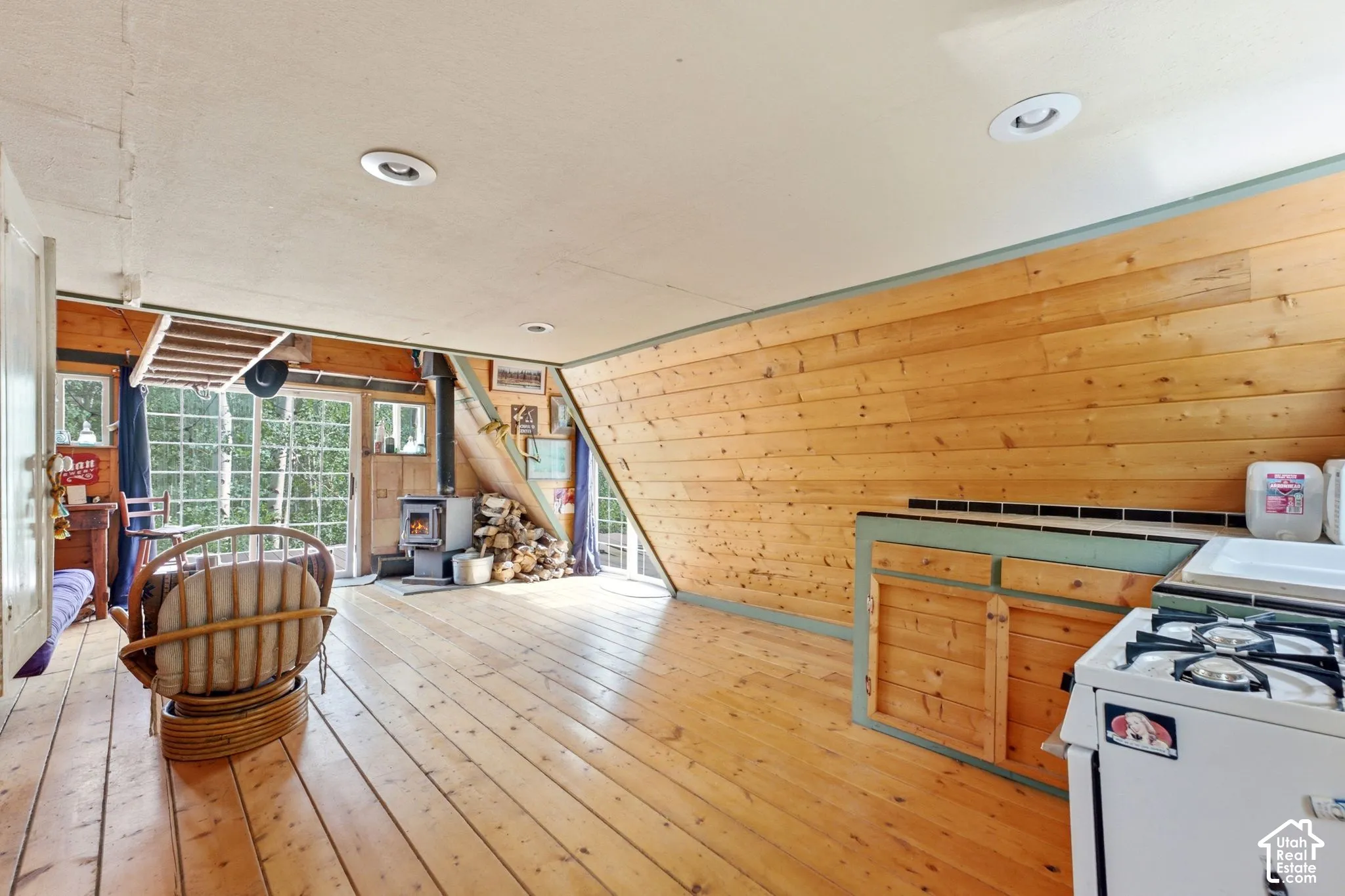 Wood-finish flooring, wood plank wall paneling, built-in cabinetry, and a freestanding oven range