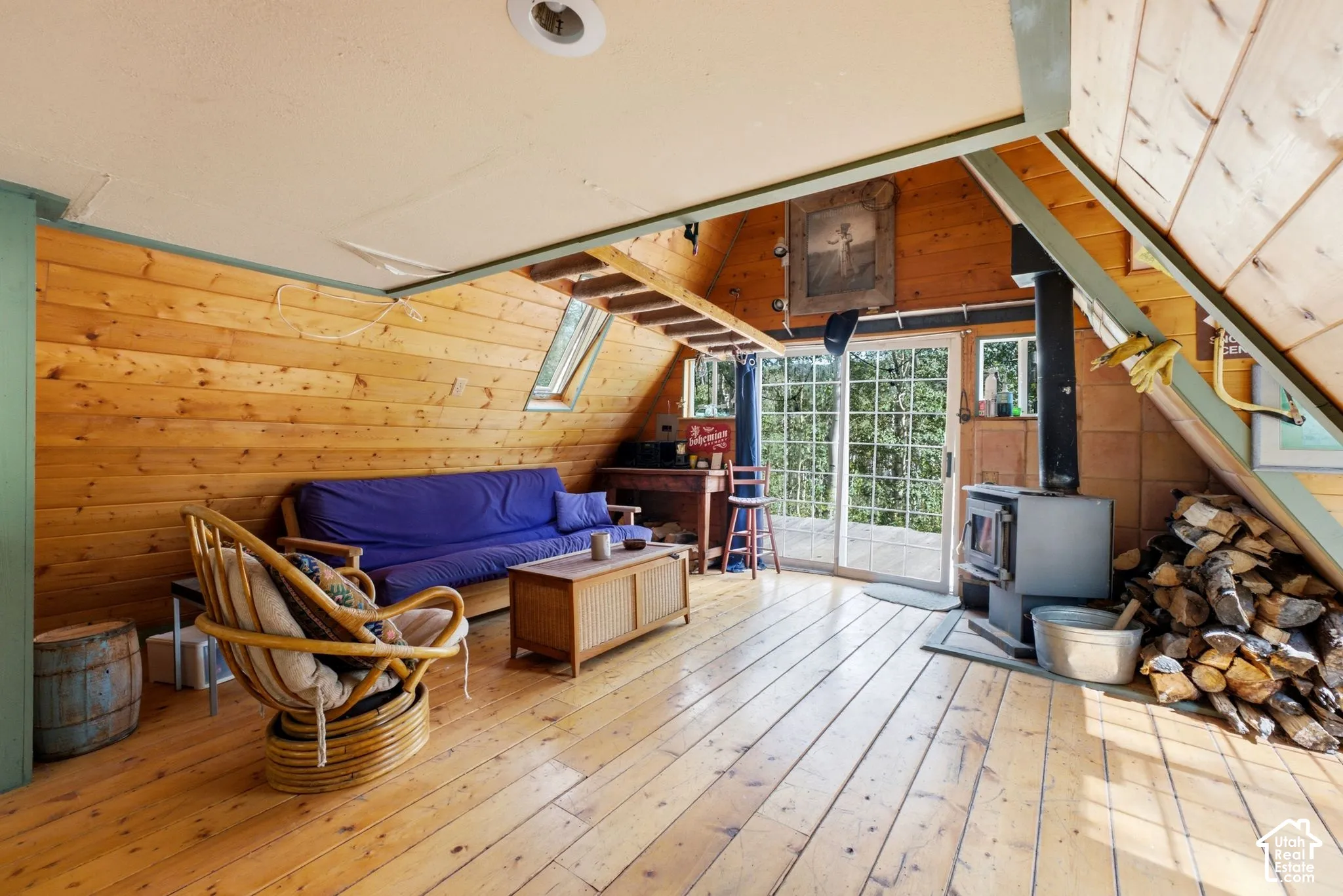 Wood-finish flooring with wood-paneled walls, exposed wood beams, and a wood-burning stove