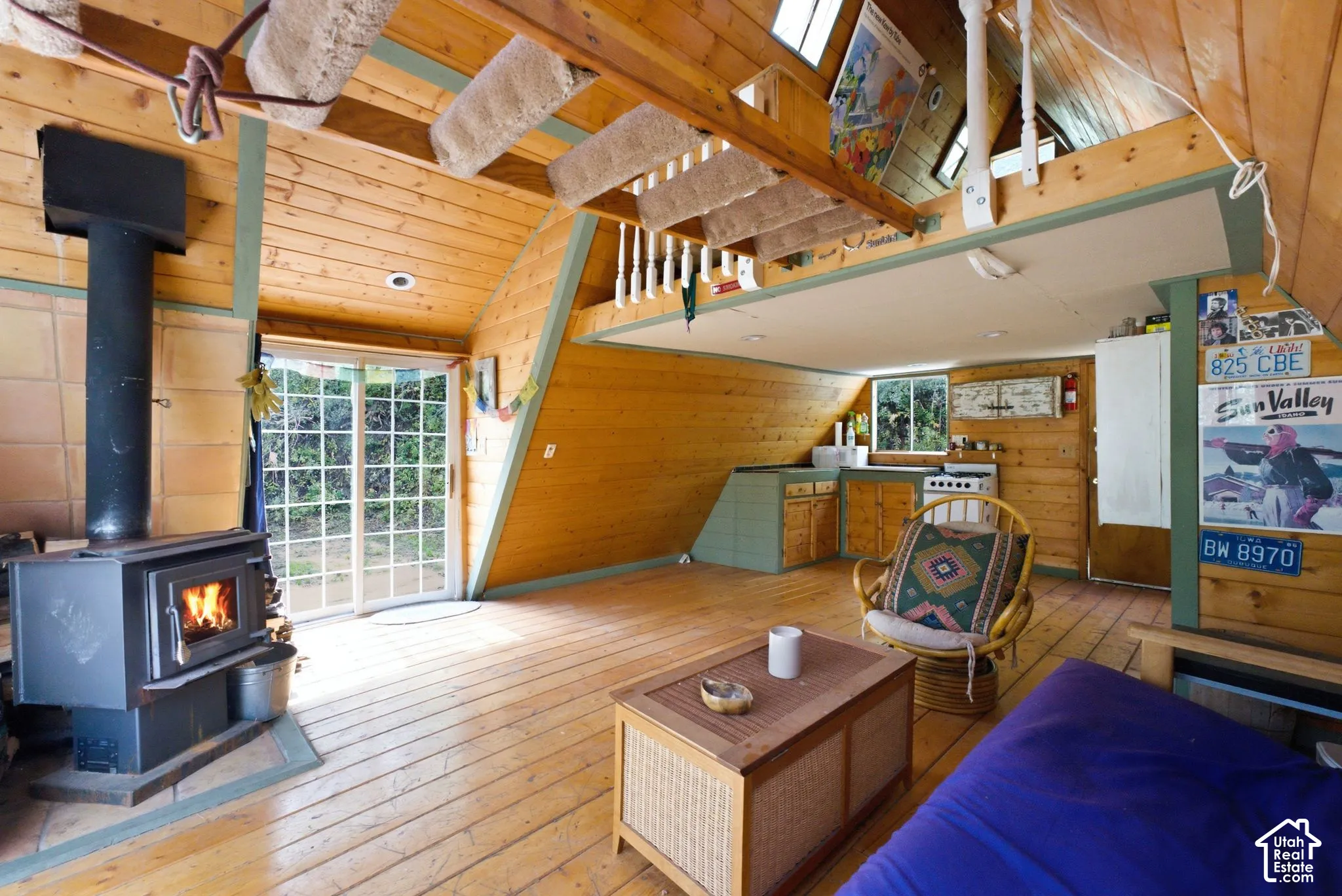 Vaulted wood-paneled ceilings, wood-finish flooring, and a wood-burning stove with a tiled hearth