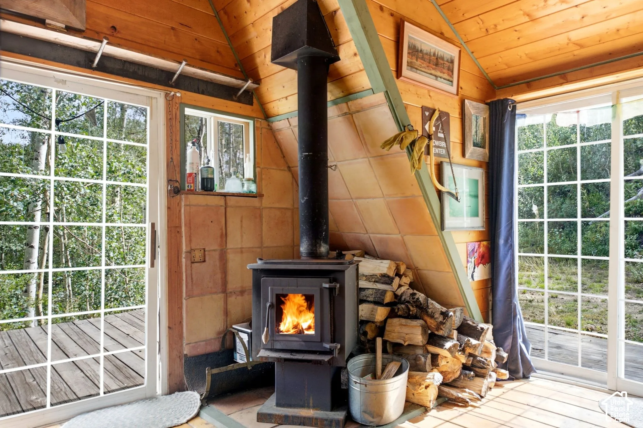 Wood-paneled ceilings, wood-finish flooring, wood-burning stove, large sliding glass doors, and a tiled wall feature