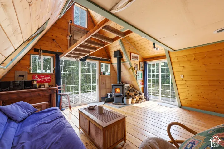 Vaulted wood-paneled ceiling, wood-finish flooring, built-in wood-burning stove, and multiple window-paned sliding doors