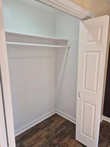 Closet with wood-finish flooring, white walls, and bi-fold doors