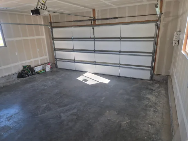 Attached garage featuring a concrete floor, automatic garage door opener, and a panel garage door