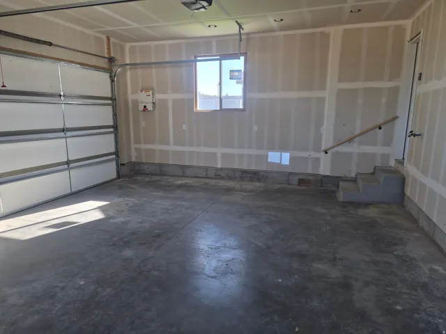 Attached garage with a sectional overhead door, concrete flooring, and a single window