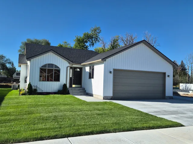 White board and batten siding, dark shingle roof, two-car garage, arched window, concrete driveway