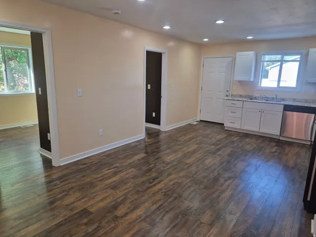 Open-concept living area with wood-finish flooring, recessed lighting, and white trim