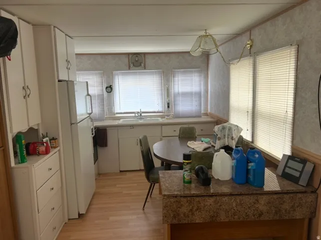 Kitchen featuring white cabinetry, a white refrigerator, a double basin sink, and wood-finish flooring