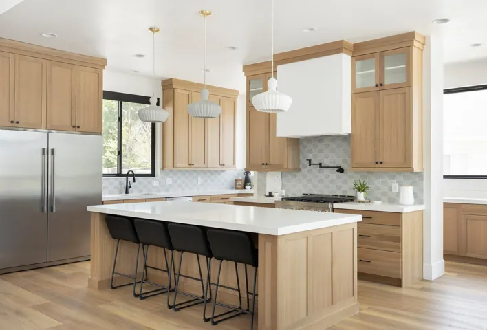 Gourmet kitchen featuring a substantial center island with seating, stainless steel appliances, wood-finish cabinetry, a patterned tile backsplash, and recessed lighting