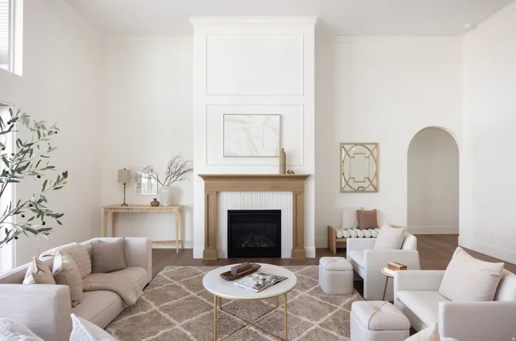 Two-story living area with a fireplace featuring a wood-finish mantel and white tile surround