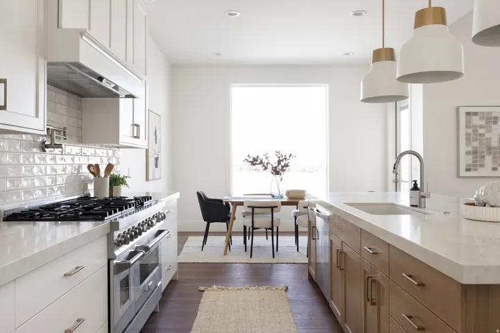 Gourmet kitchen with professional-grade range, tiled backsplash, large center island with integrated sink, and white upper cabinetry