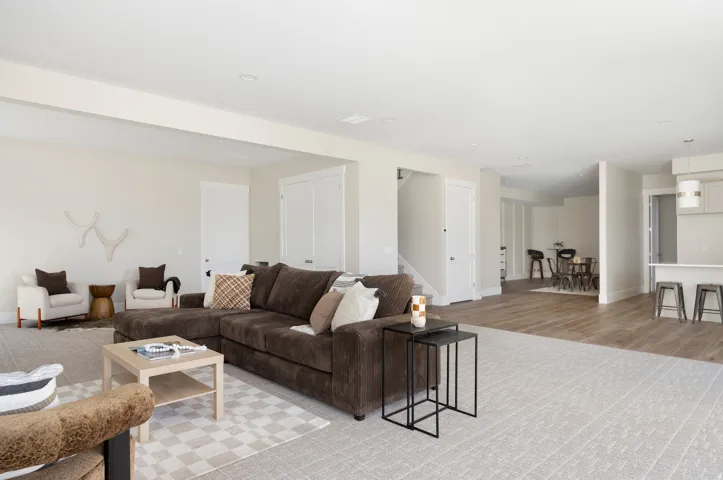 Spacious open-concept living area featuring light-toned walls, recessed lighting, and a blend of carpeting and wood-finish flooring