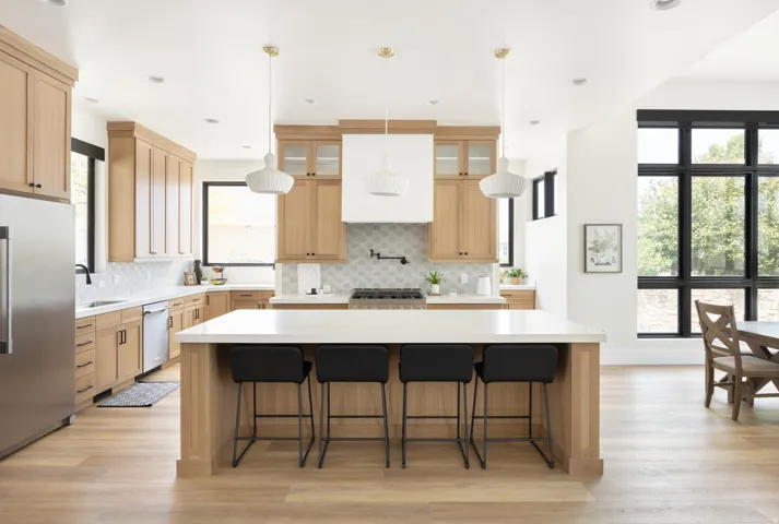 Chef's kitchen featuring warm wood cabinetry, stainless steel appliances, quartz countertops with subway tile backsplash, and a generous center island with seating