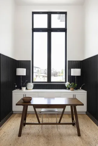 Tall window with black trim, built-in lower cabinetry, black vertical paneling, and wood-finish flooring