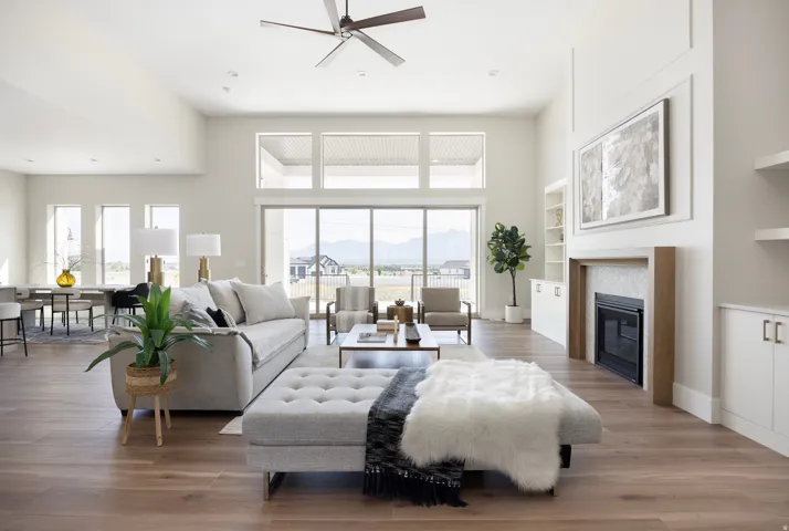 Vaulted ceiling living area with wood-finish flooring, a contemporary fireplace with mantel, built-in shelving, and large sliding glass doors