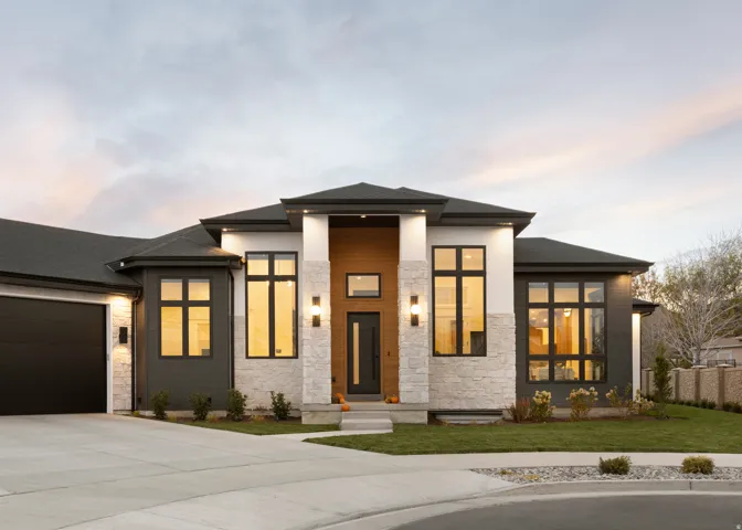 Modern exterior with large black-framed windows, stone and wood-finish accents, a dark garage door, and an integrated walkway