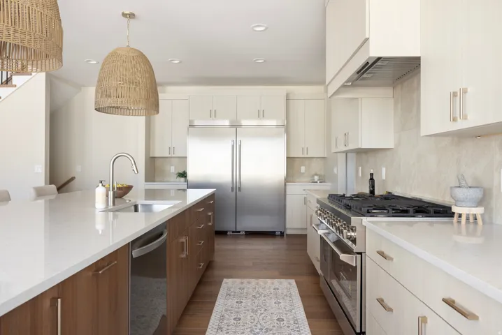 Gourmet kitchen with stainless steel appliances, white countertops, dual-tone cabinetry, and wood-finish flooring