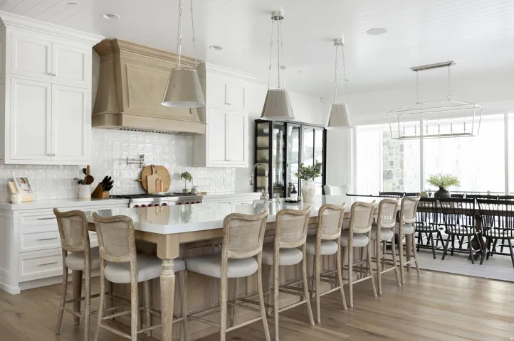 Kitchen featuring extensive white cabinetry, a large center island with seating, a wood-finish range hood, tile backsplash, and light wood-finish flooring