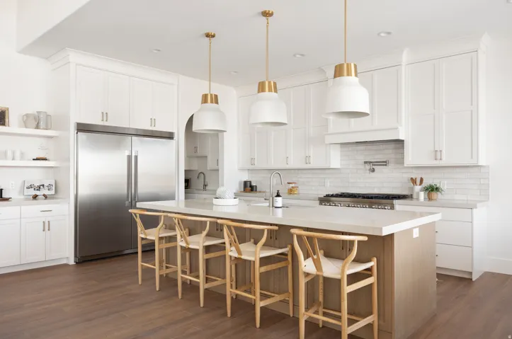 White cabinetry with gold hardware, stainless steel refrigerator, and wood-finish flooring