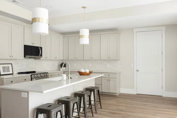 Modern kitchen featuring light cabinetry, stainless steel appliances, a center island with countertop seating, wood-finish flooring, and pendant lighting