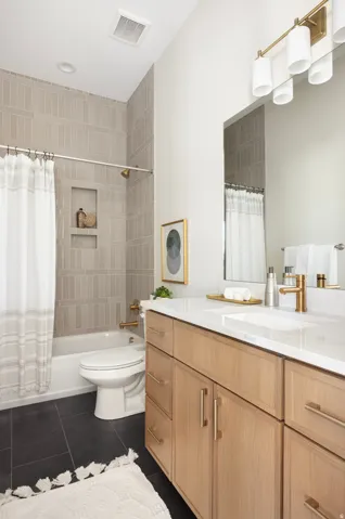 Modern bathroom featuring a wood-finish vanity with dual-sink white quartz countertop, polished chrome hardware, and framed mirror with integrated lighting