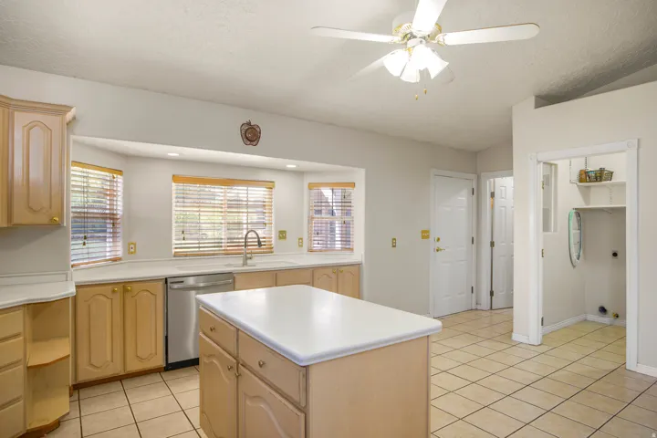 Kitchen featuring a central island, wood-finish cabinetry, tile flooring, a built-in dishwasher, and a ceiling fan