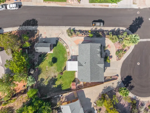 Gray shingle roof, concrete driveway, attached carport, detached shed, and a manicured lawn