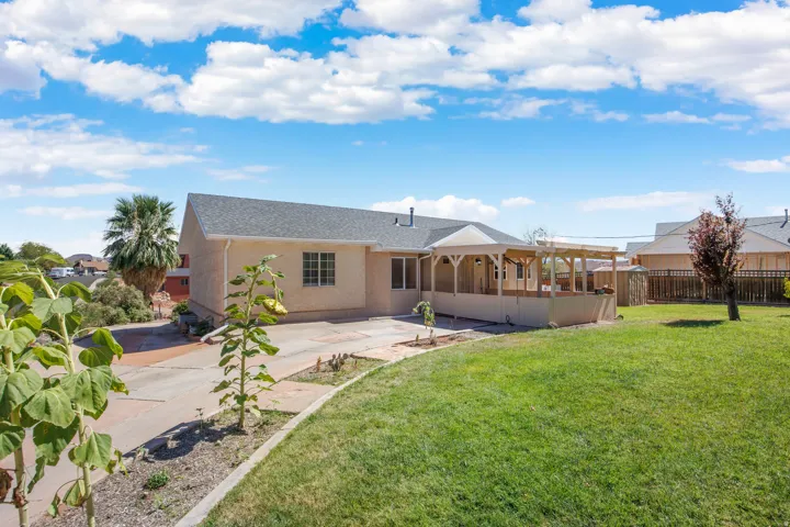 Expansive backyard featuring a manicured lawn, a large covered deck, a separate pergola, and a visible storage shed