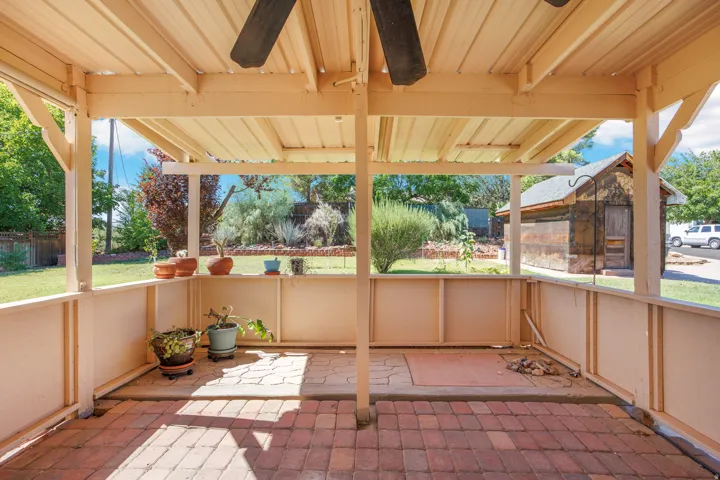 Covered patio featuring a brick-paver floor, a ceiling fan, and a corrugated metal roof